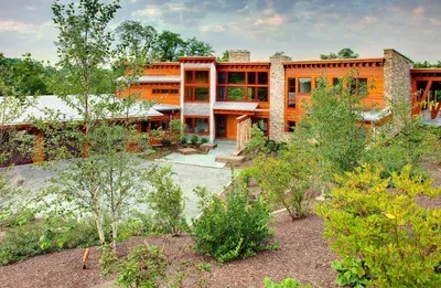 A large house with a lot of windows is surrounded by trees and bushes.