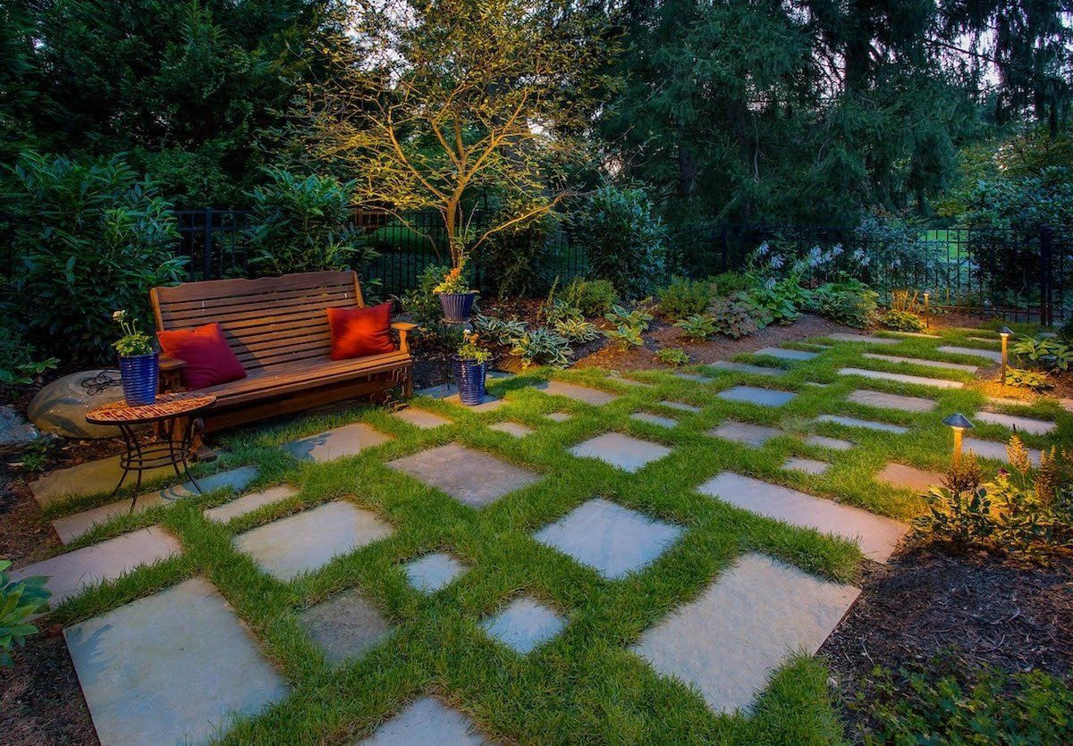 A wooden bench is sitting on top of a lush green lawn in a garden.