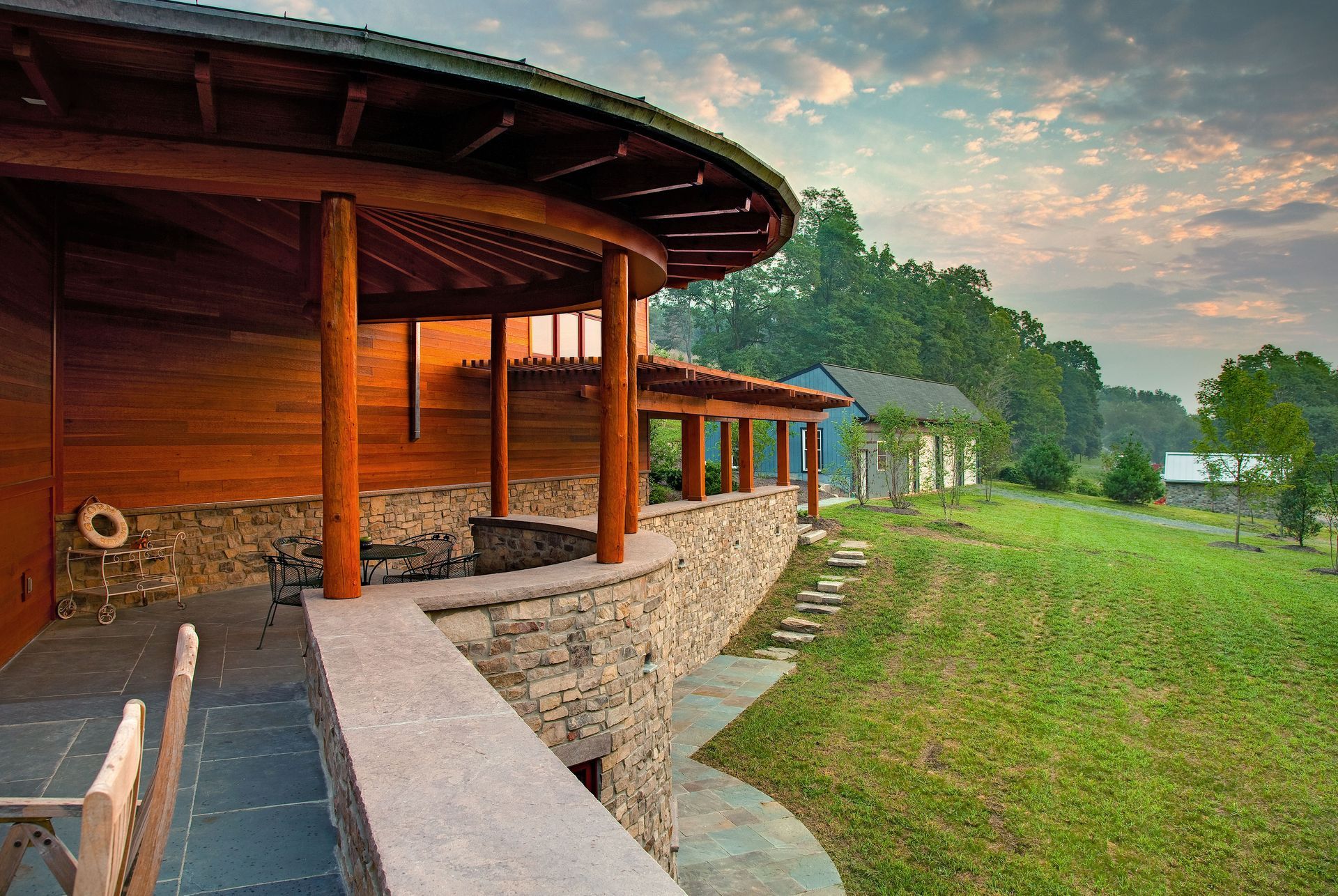 A wooden house with a stone wall and a wooden roof is sitting on top of a grassy hill.