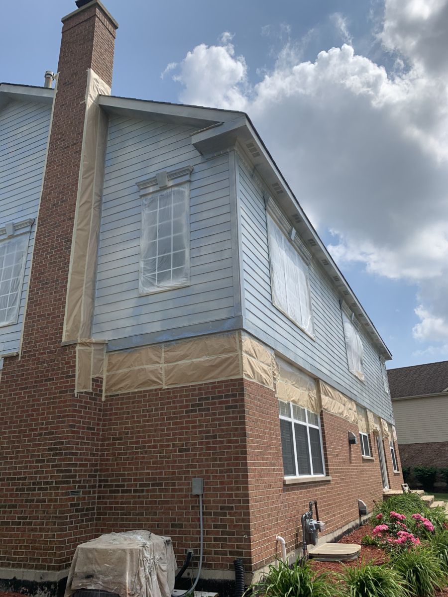 Two-story brick and gray-sided house with a chimney under a cloudy sky