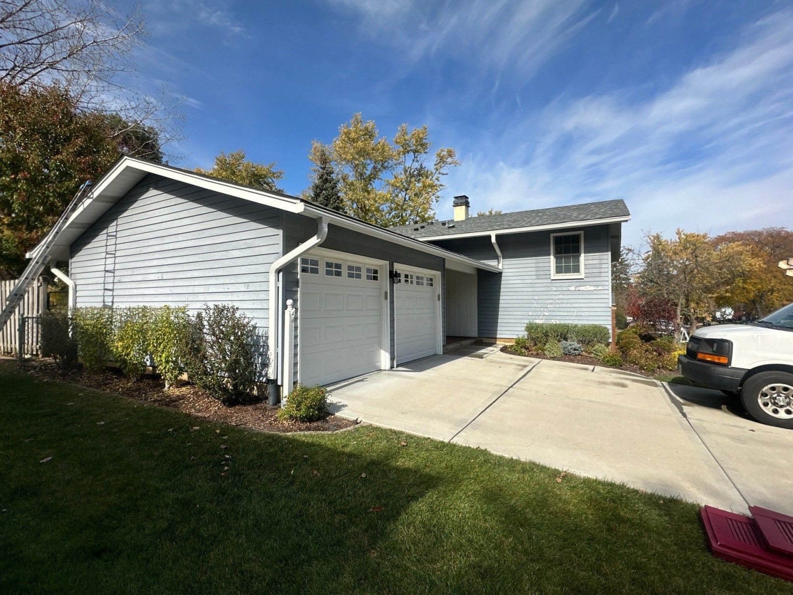 Suburban house with attached garage, driveway, and parked SUV on a sunny day