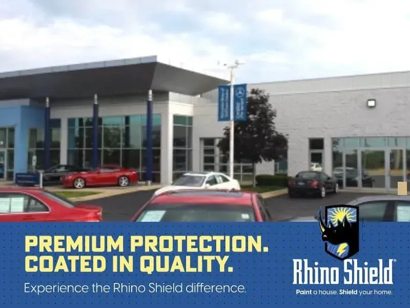Car dealership exterior with Rhino Shield sign and banner reading “Premium Protection. Coated in Quality.”