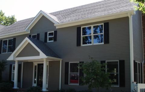 Two-story beige house with black shutters, white trim, and a covered front porch