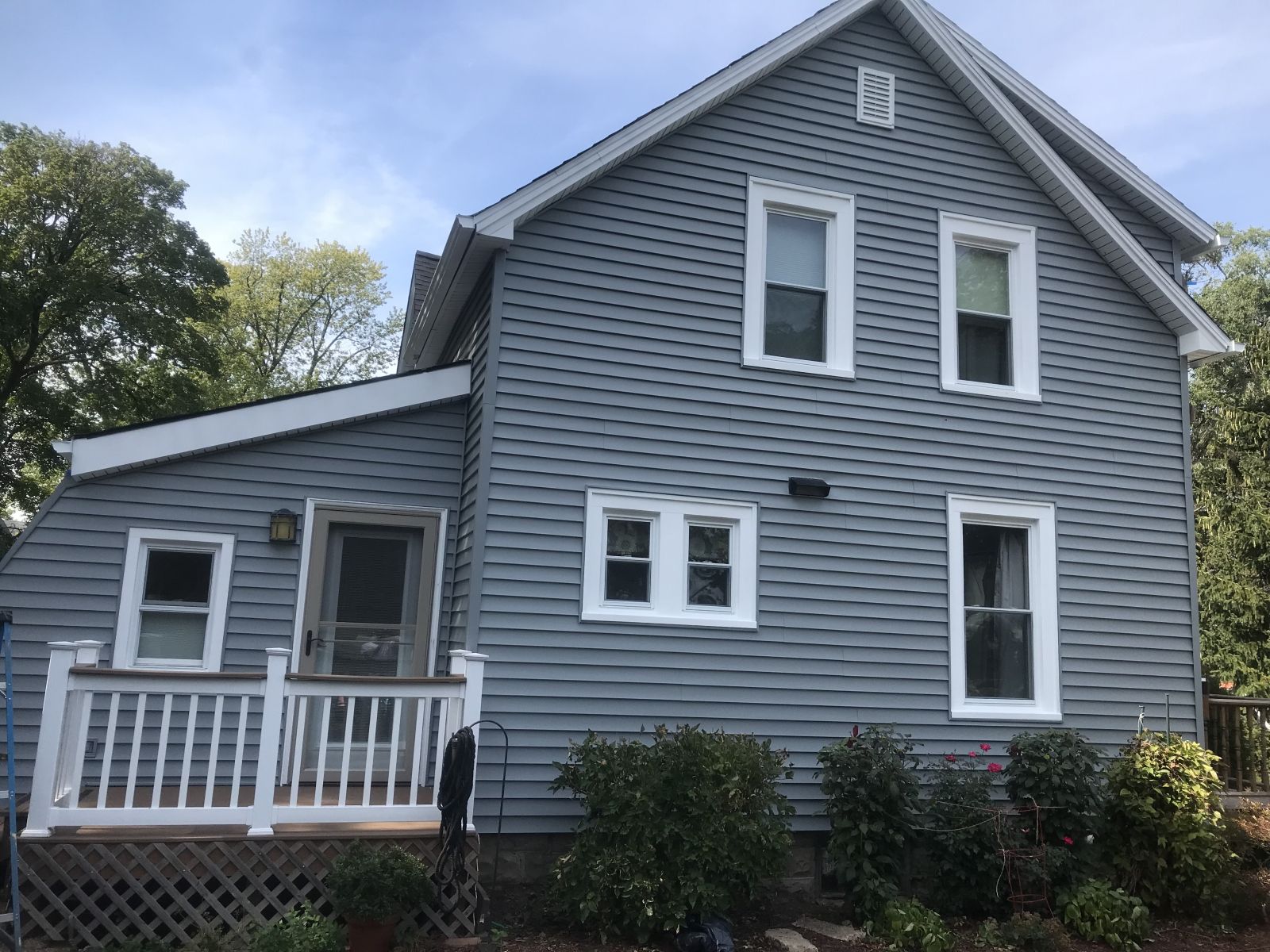 Gray two-story house with white trim and a small porch on a sunny day
