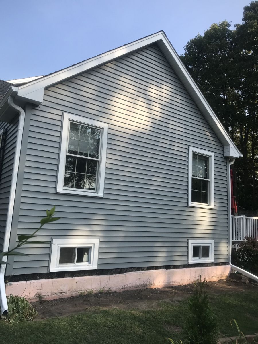 Gray house exterior with white trim, two windows, and a small porch in daylight