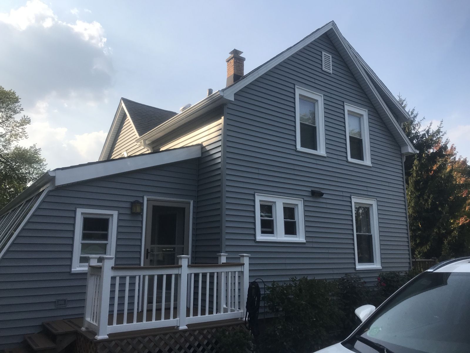 Gray two-story house with white trim and a small front porch, viewed from the side.
