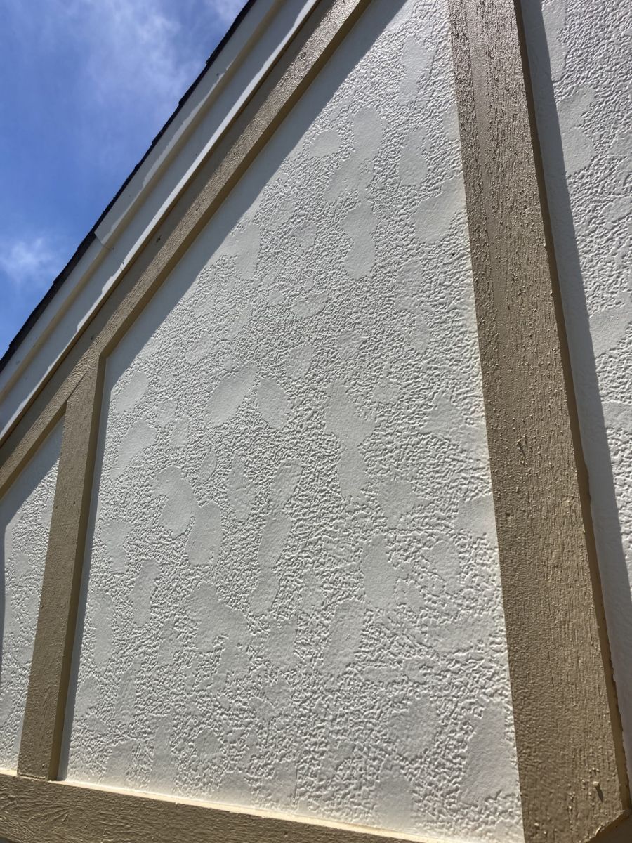 White stucco wall with brown trim against a blue sky