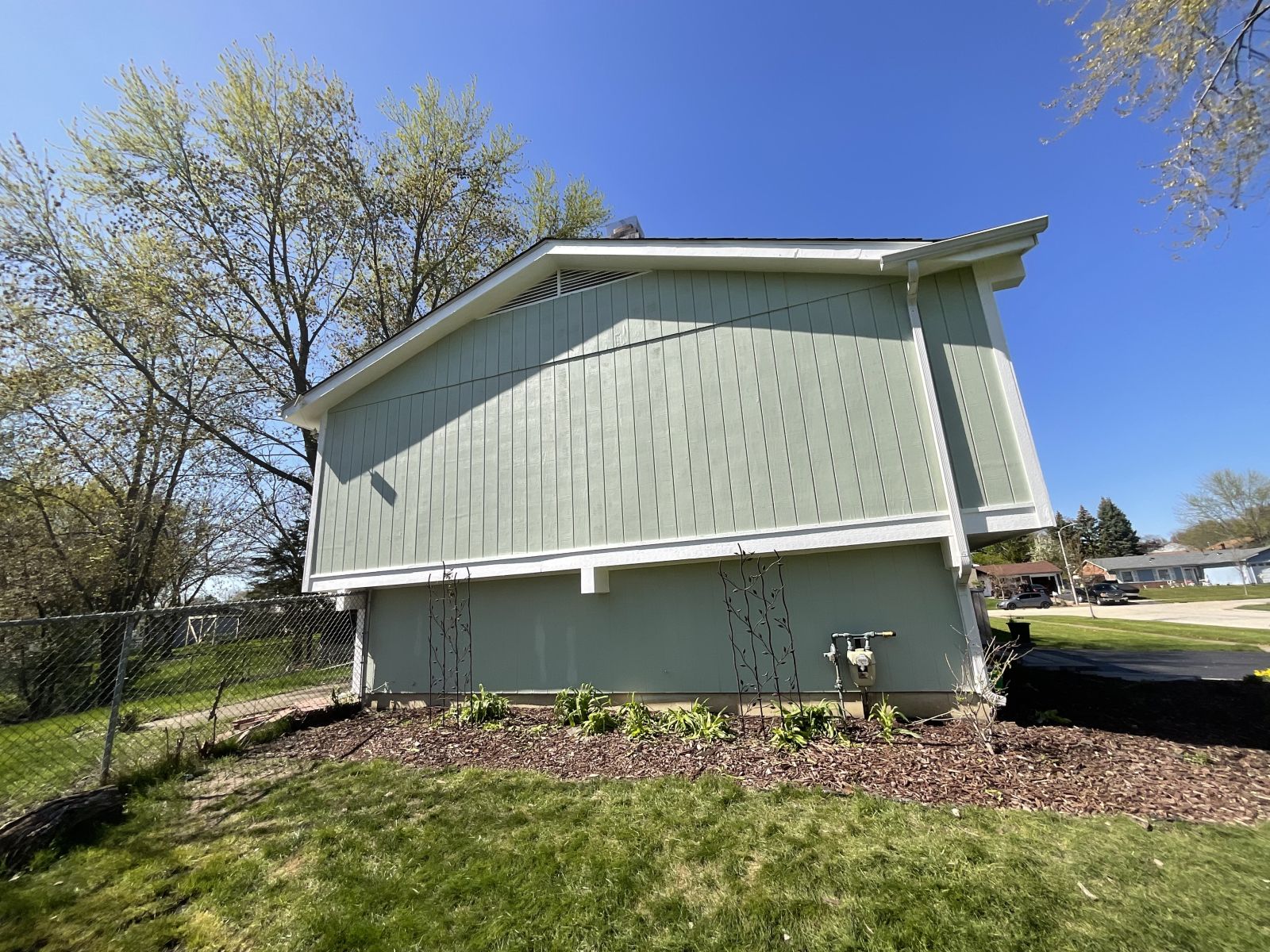 Small light-green house with a slanted roof, seen from the side under a blue sky.