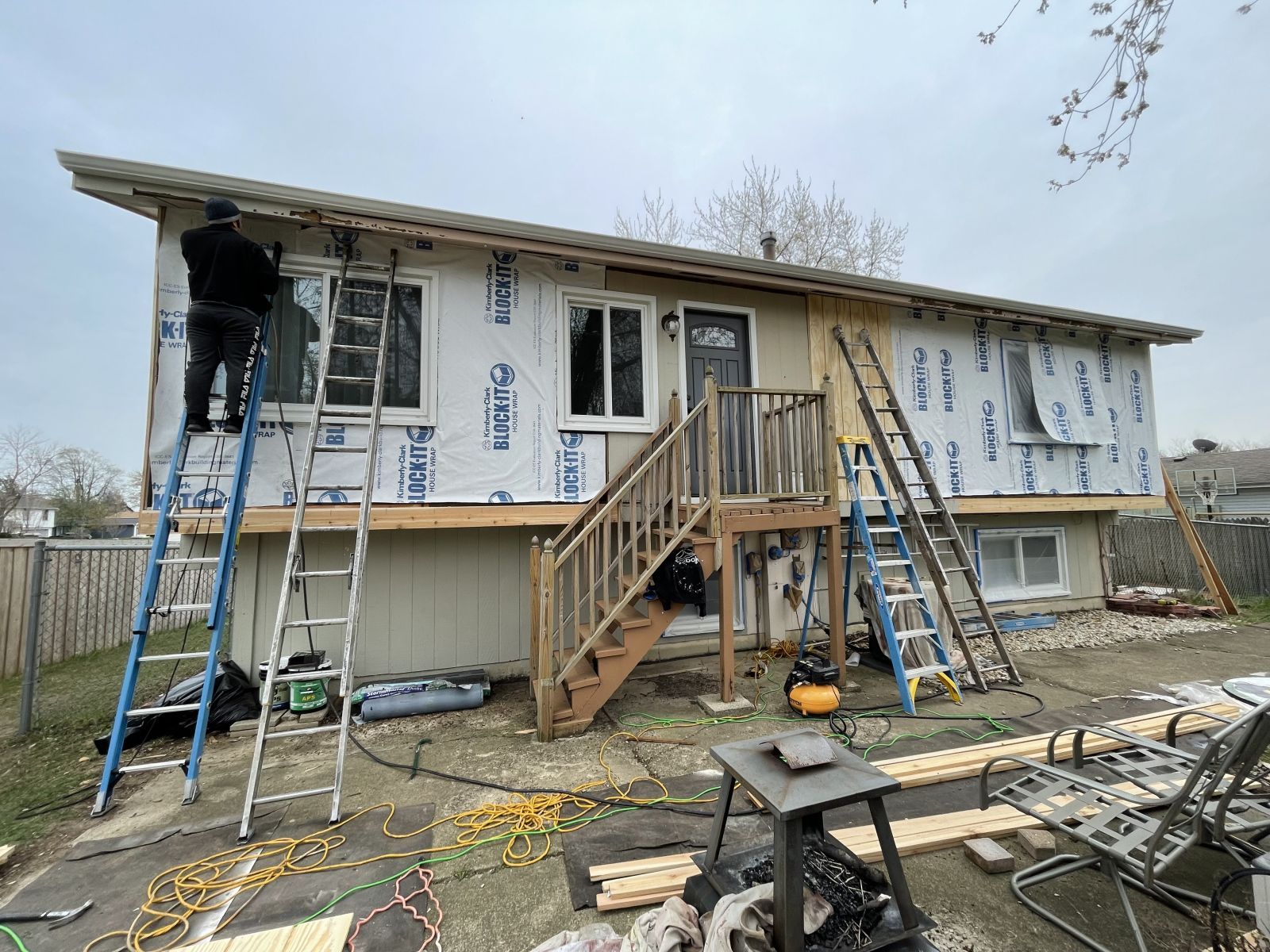 House under renovation with workers on ladders and a central wooden staircase