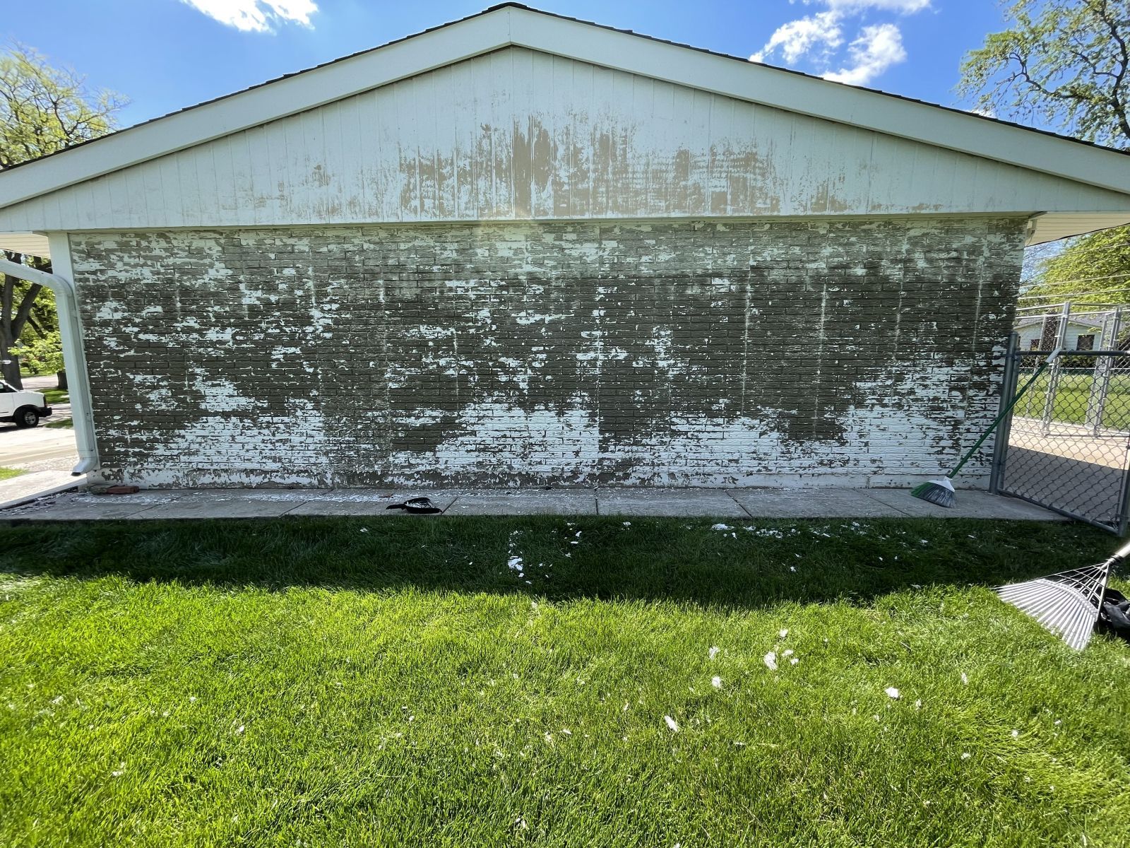 White house with heavily weathered, peeling front wall above a green lawn under a blue sky.