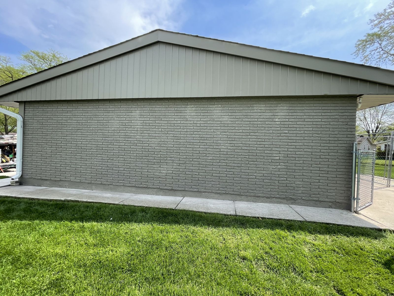 Closed gray roll-up door on a light gray building beside a grassy lawn on a sunny day