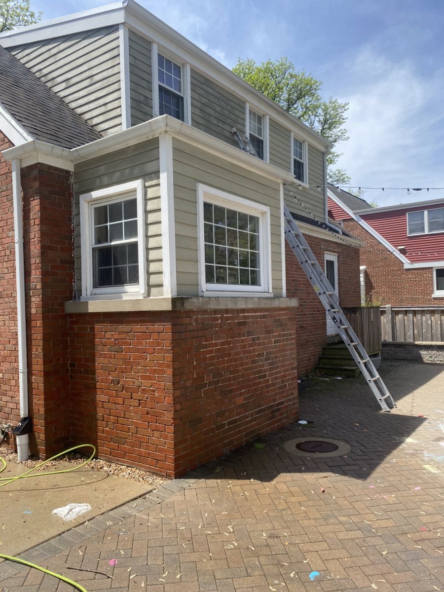 Brick and beige two-story house exterior with a ladder leaning against the side
