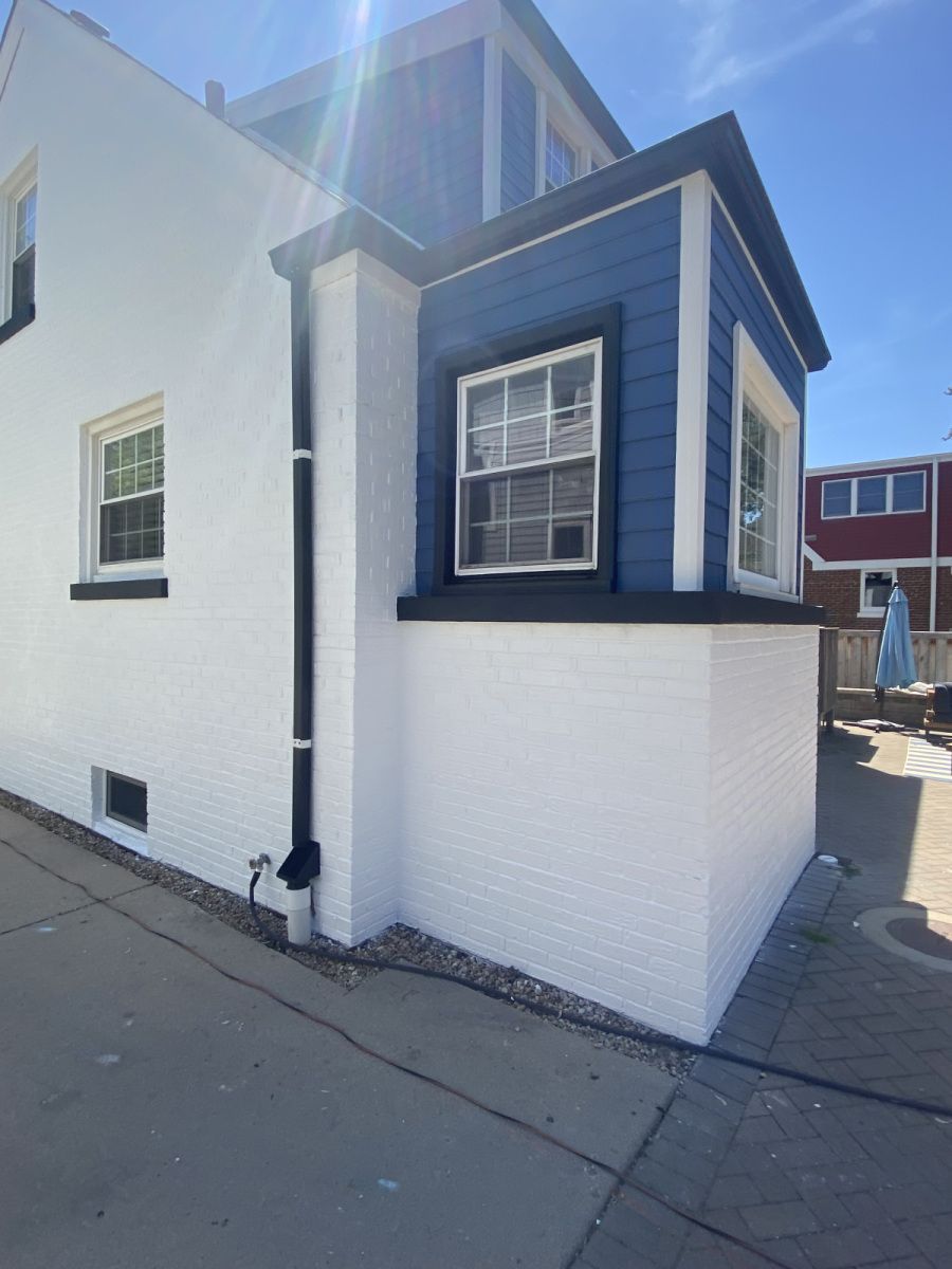White building corner with blue-trimmed window on a sunlit street
