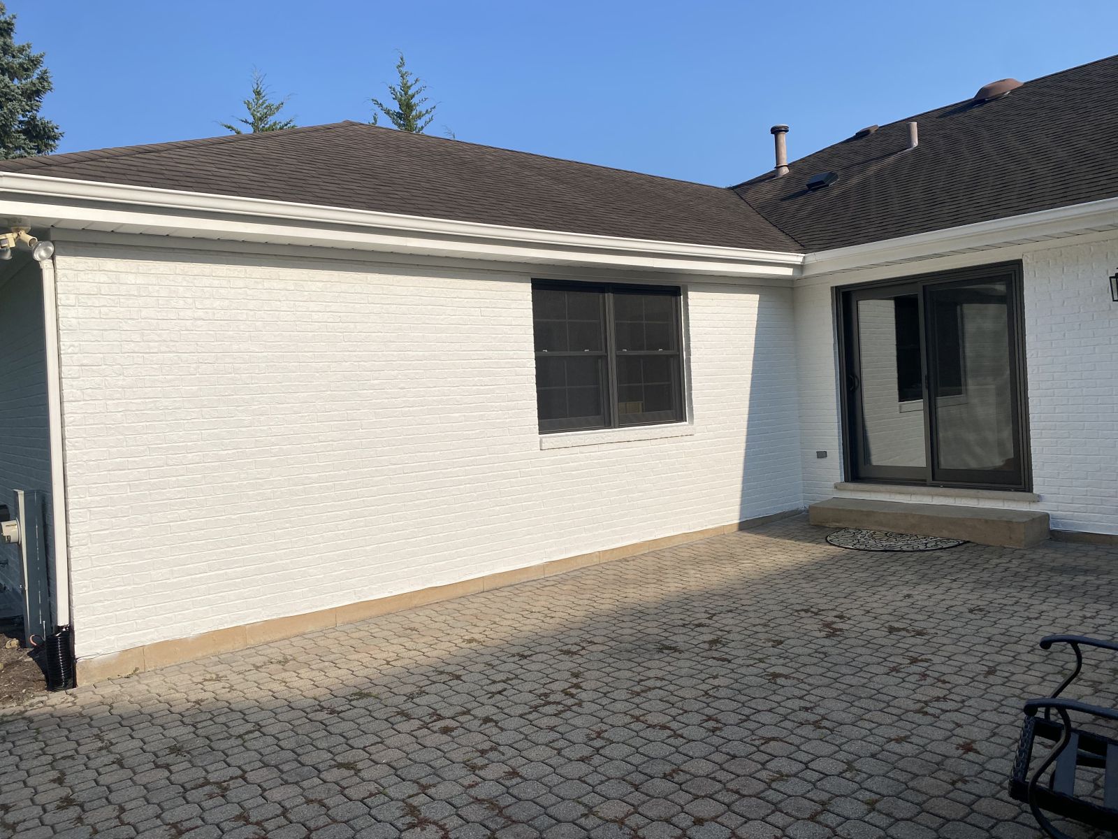 White stucco house with tiled roof and paved courtyard, seen in bright sunlight
