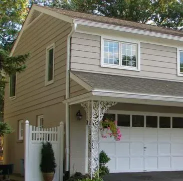 Tan two-story house with white garage door, porch, and hanging flower basket