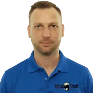 Man in a blue polo shirt against a white background, facing forward with a neutral expression