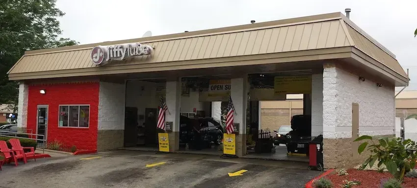 Drive-thru restaurant exterior with tan roof, red wall, and wet pavement on a rainy day