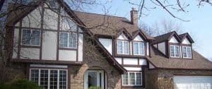 Tudor-style house with white trim, steep gabled roof, and attached garage
