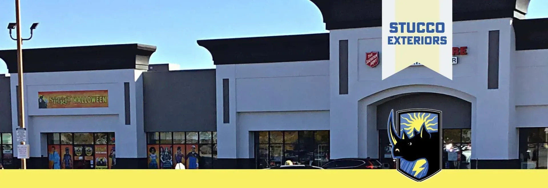 Commercial storefront with a STUCCO EXTERIORS sign and dark gray facade under a blue sky