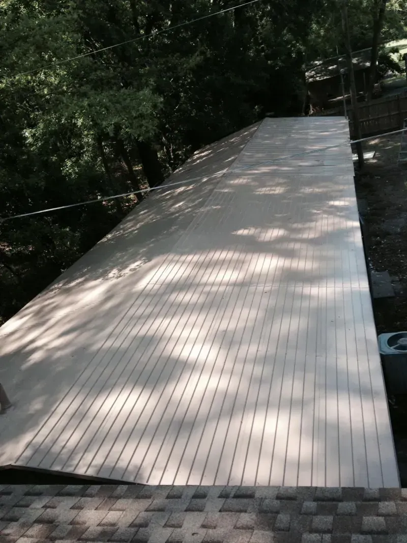 Long wooden boardwalk through a wooded area, lit by dappled sunlight.