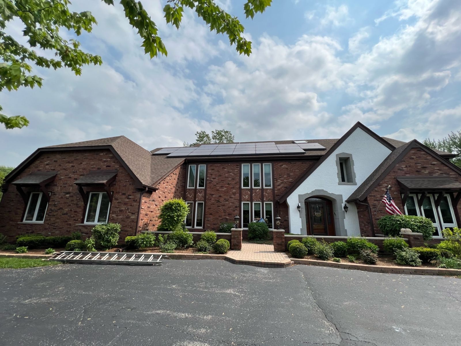 Wide brick building with a central white entrance, solar panels, and landscaped grounds under a cloudy sky