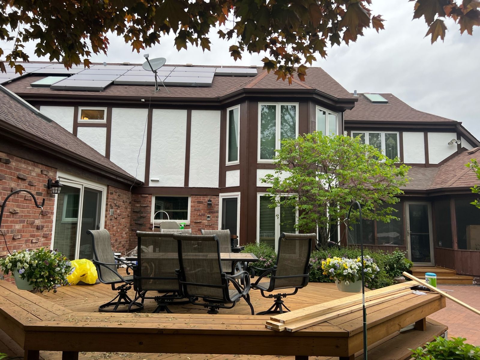 Backyard deck with patio table and chairs beside a brick and white house
