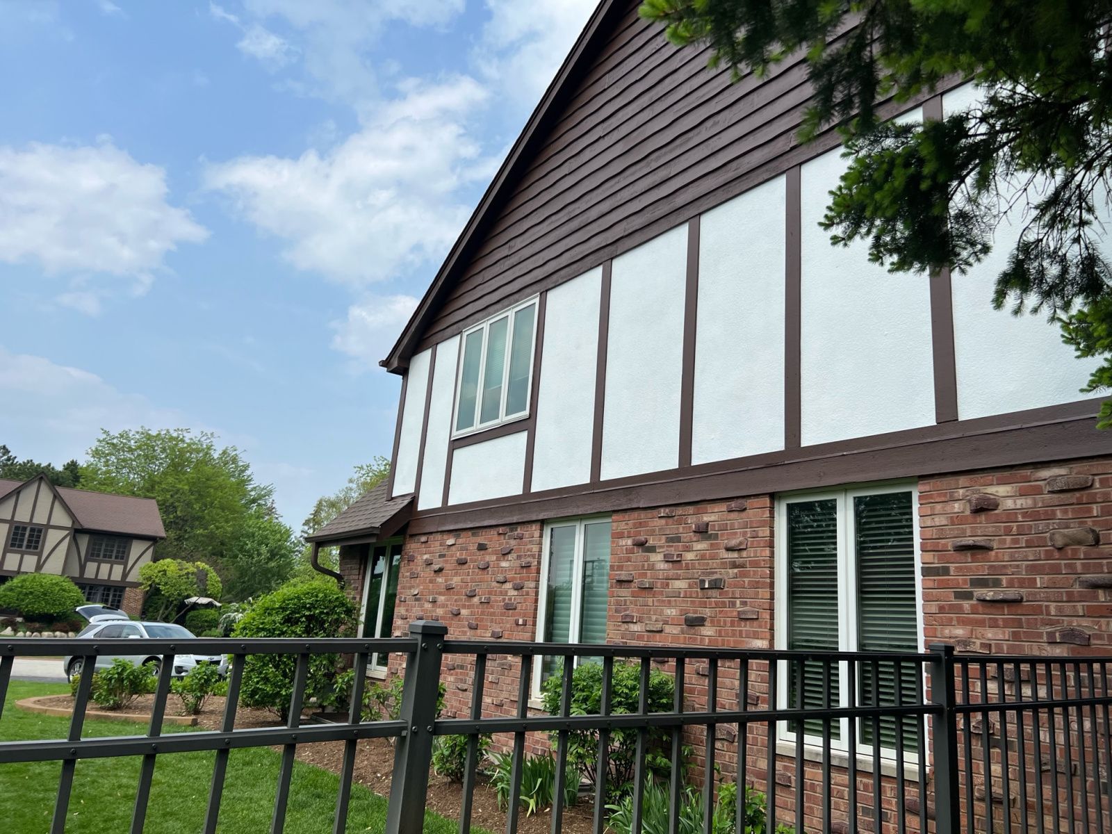 Brick and white apartment building with black railing and blue sky