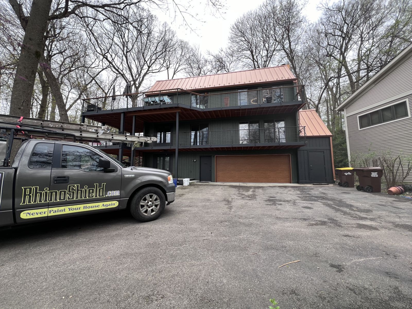 Dark two-story house with a brown garage and a parked black service truck in the driveway