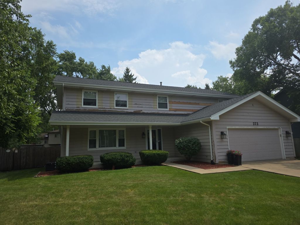Two-story suburban house with gray siding, front lawn, and attached two-car garage