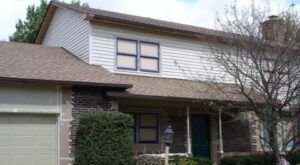 Two-story suburban house with white siding, brown roof, and a garage, seen from the front