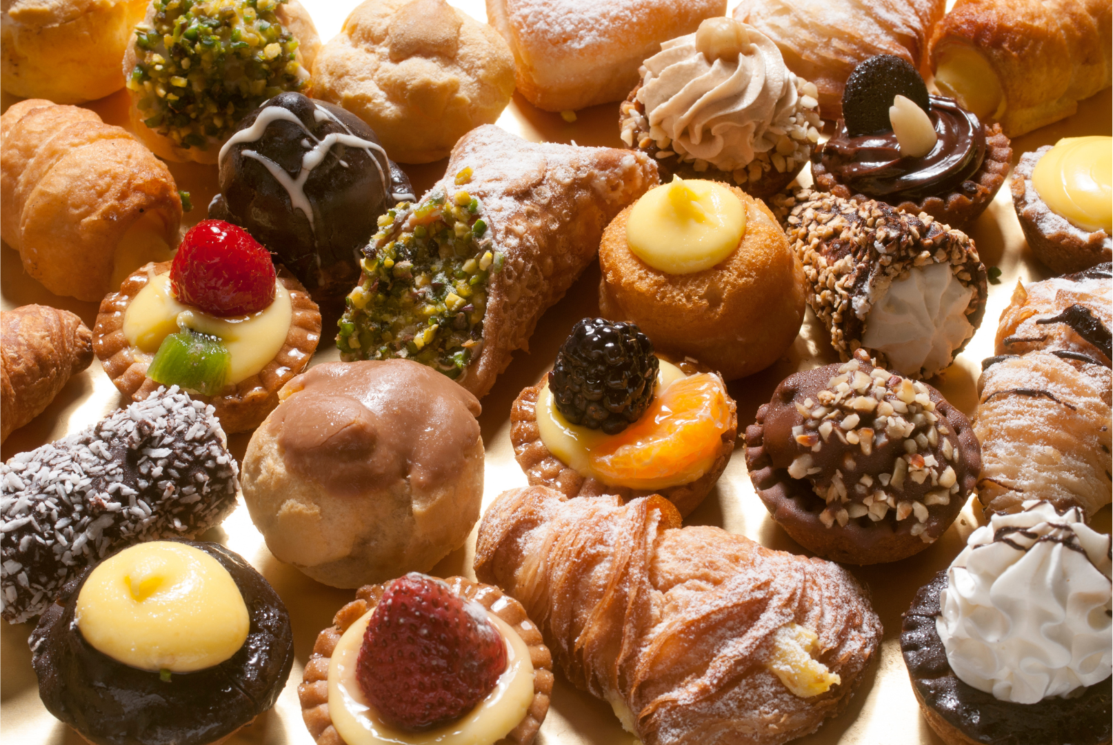 Assortment of colorful mini pastries, including tarts, cannoli, and cream-filled treats.