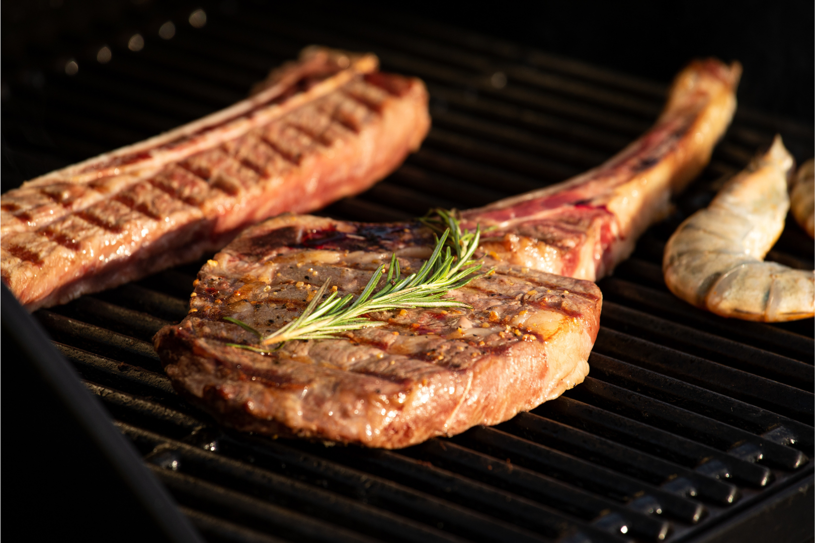 Grilled steak and shrimp with rosemary on a hot grill.