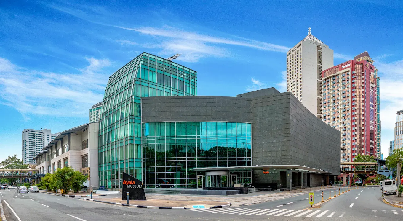 Modern glass-and-stone building with turquoise facade beside tall high-rises on a city street