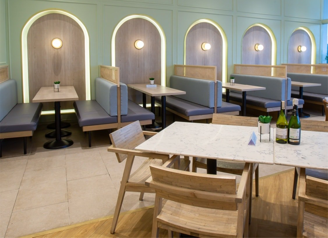 Empty modern café with blue booths, small tables, and white pendant lights