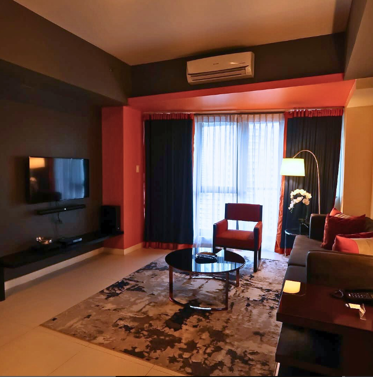 Stylish living room with red accents and comfortable seating, perfect for relaxing during a staycation.