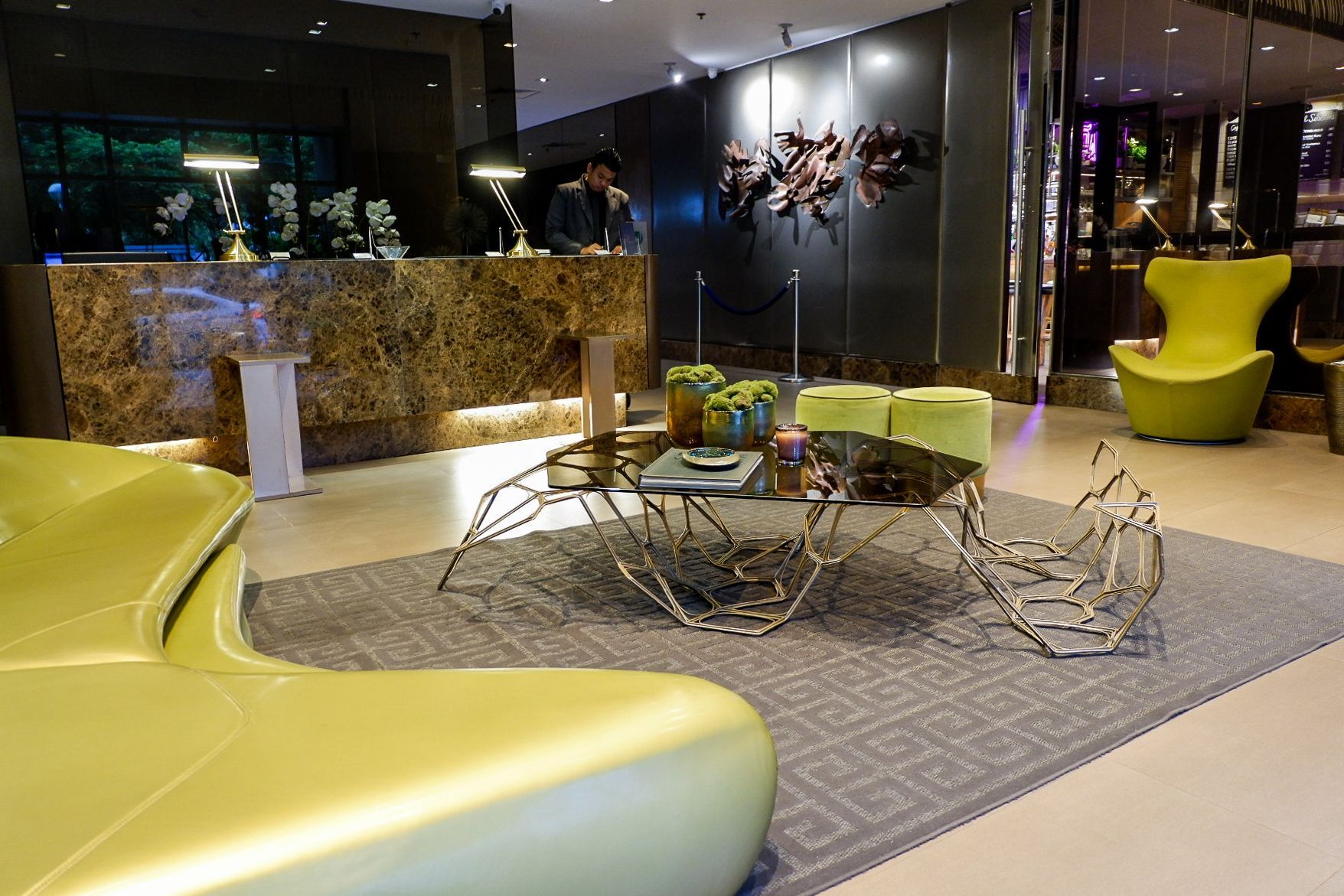 Lobby of KL Tower Serviced Residences Makati with a marble front desk, lime green curved sofas, and a geometric coffee table