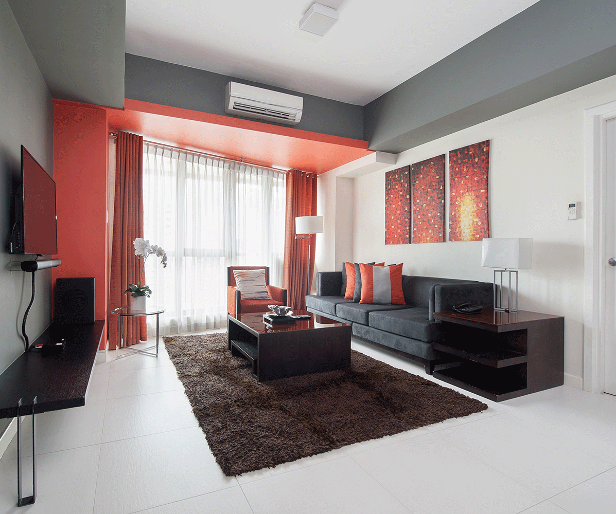 Modern living room with red accents, gray sofa, and wall art at KL Serviced