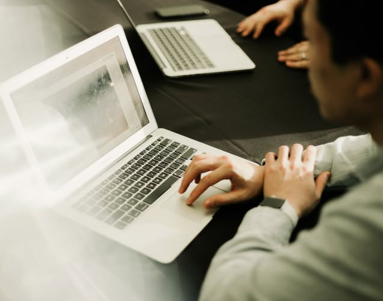 Business meeting in progress with participants using laptops in a hotel meeting space.