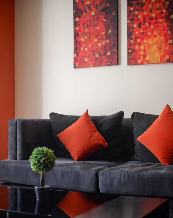 Modern living room with gray sofa, red cushions, and abstract wall art