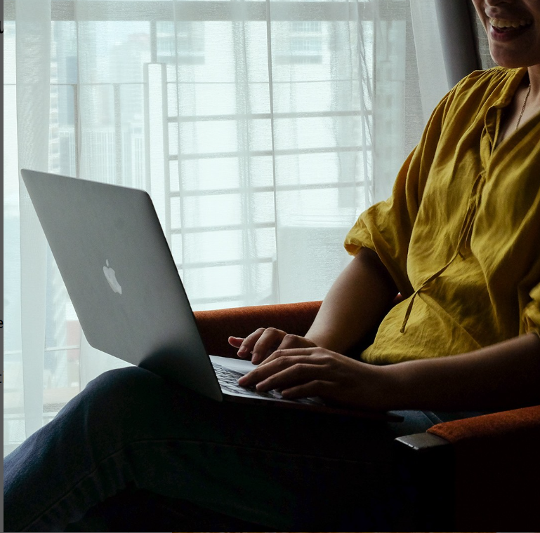 Person working on laptop in comfortable hotel workspace with natural lighting, perfect for business travelers.