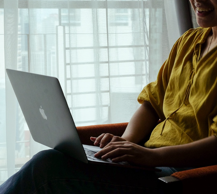 Smiling woman using MacBook laptop on sofa at KL Serviced Residences Makati