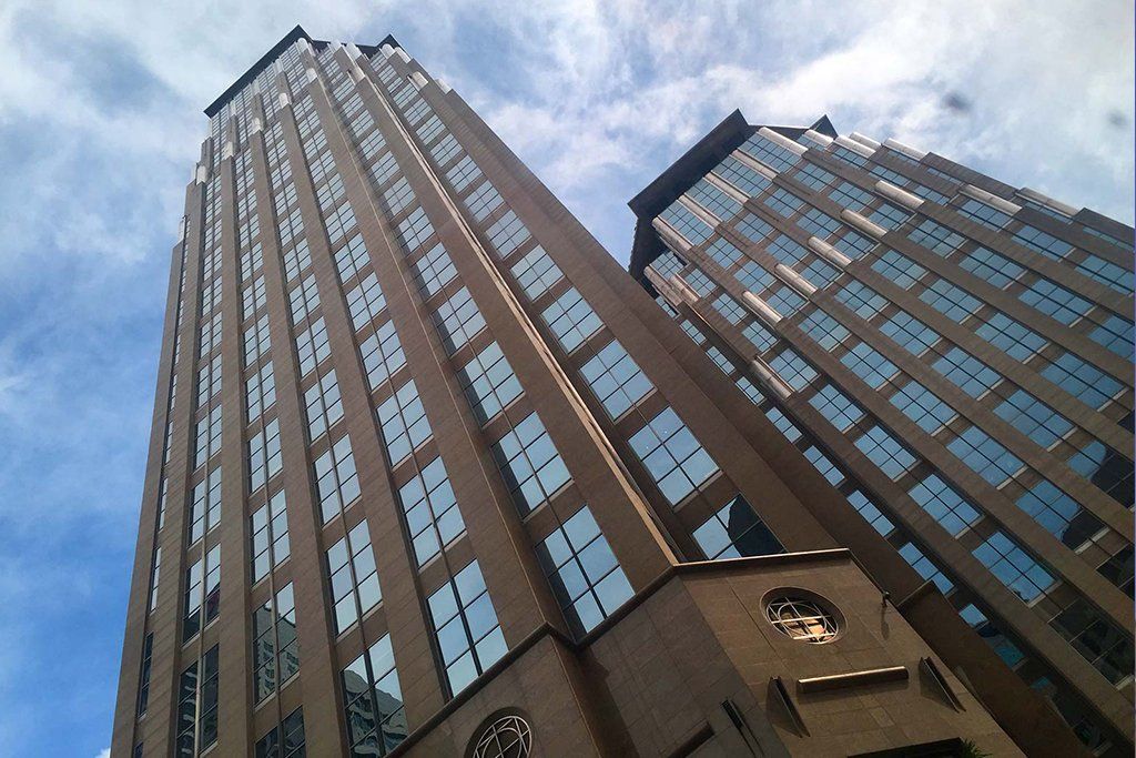 Modern high-rise building with glass facade viewed from street level in an urban setting