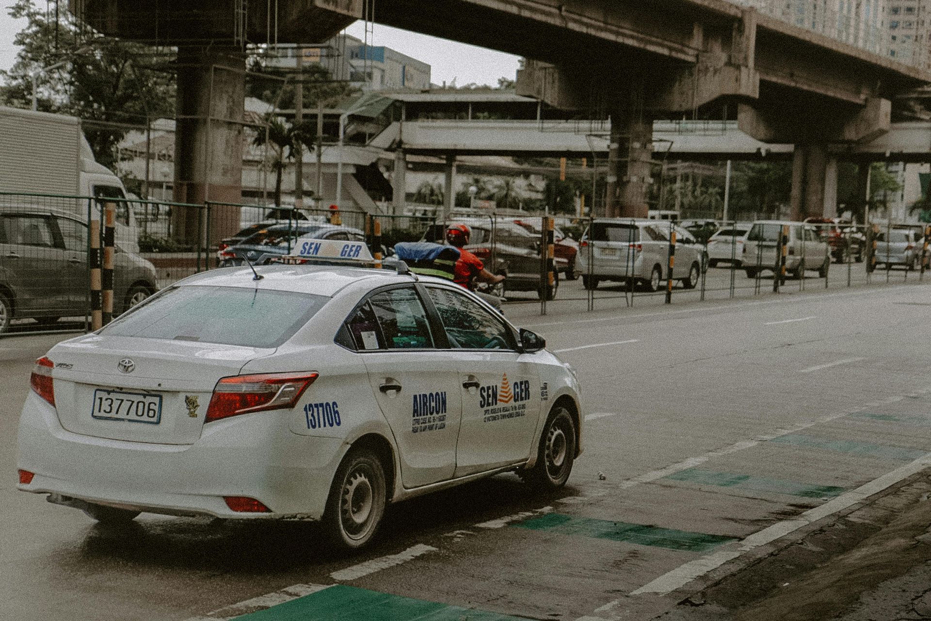 White taxi cab on busy Makati street near elevated expressway