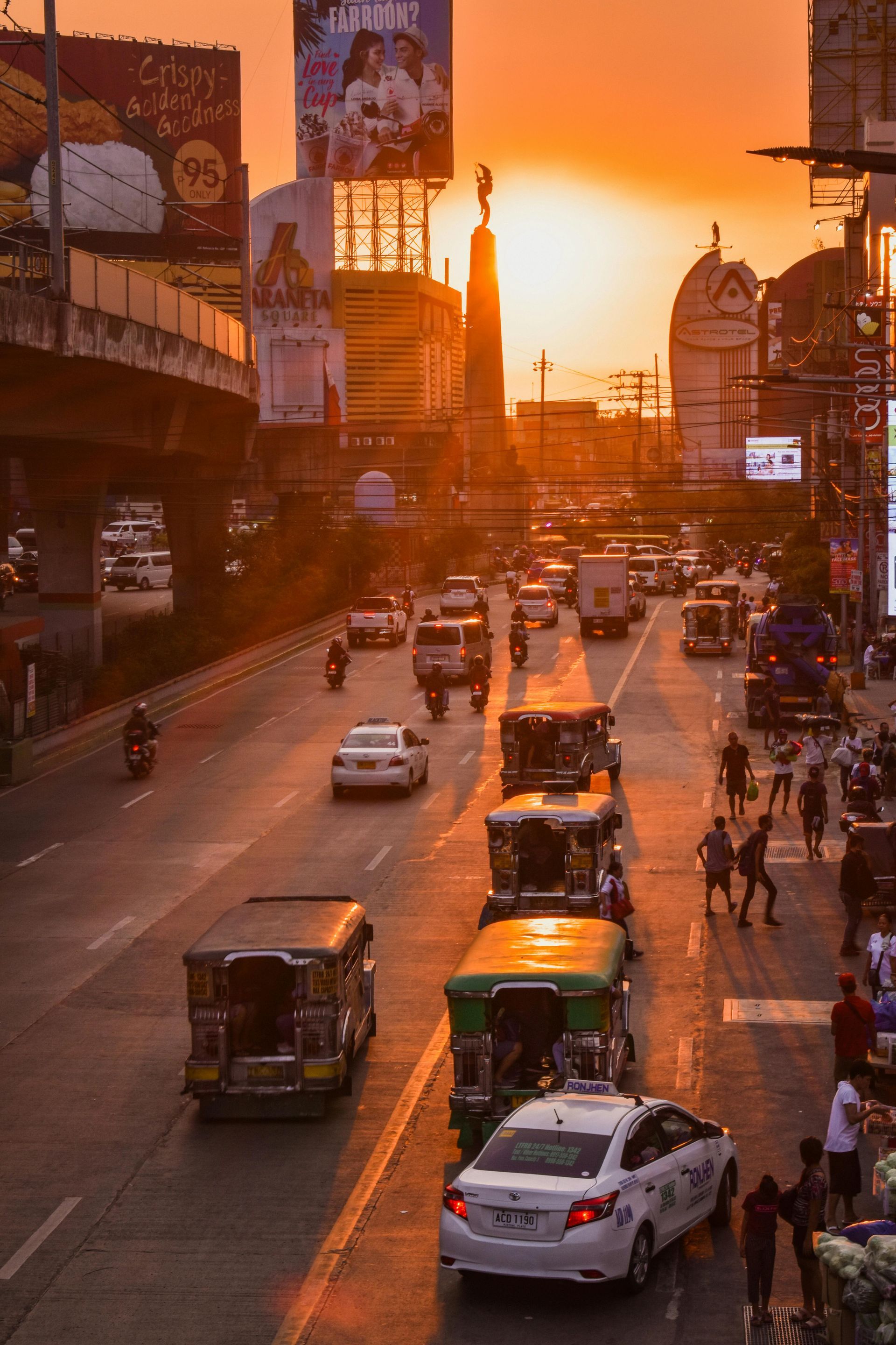 Busy Manila street at sunset with jeepneys and city billboards