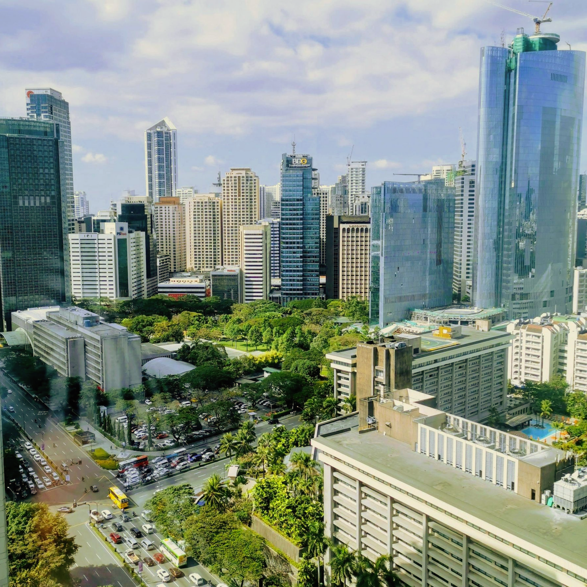 City skyline with skyscrapers, green park, and busy streets under a cloudy sky.