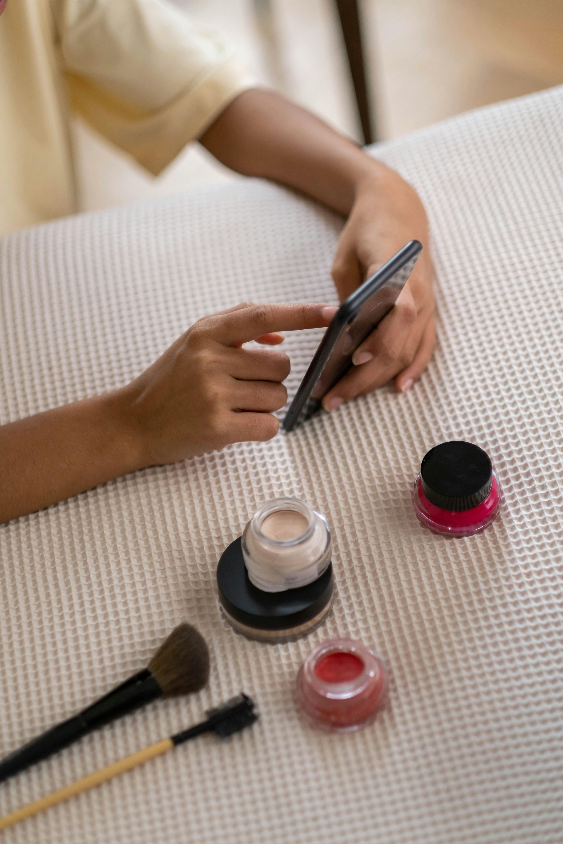 Woman using smartphone beside makeup products at KL Serviced Residences