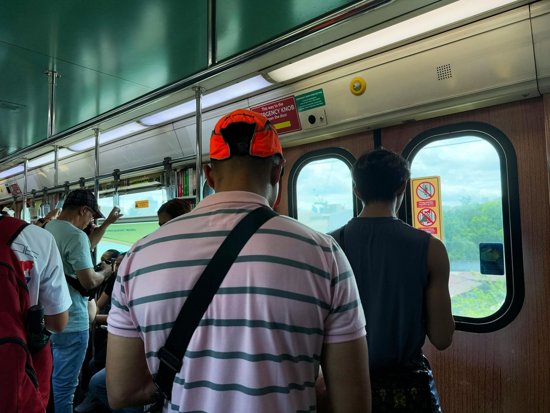 Crowded train interior with standing passengers near window
