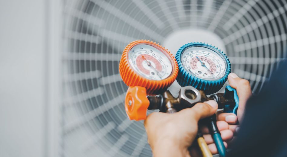 HVAC technician using gauges on an air conditioning unit.