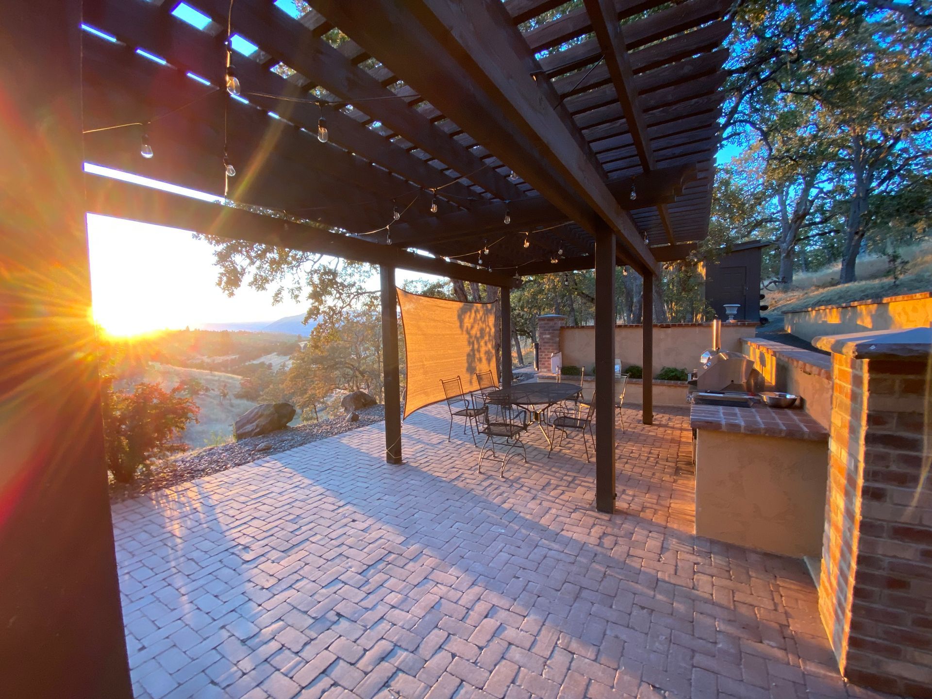 A patio with a pergola and a view of the sunset.
