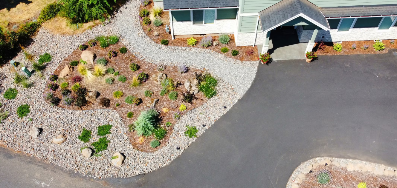 Aerial view of a house with a landscaped yard and a curved driveway.